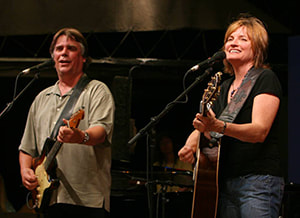 A man and woman stand on a stage with guitars. Photo Credit: Archbold Music Commission